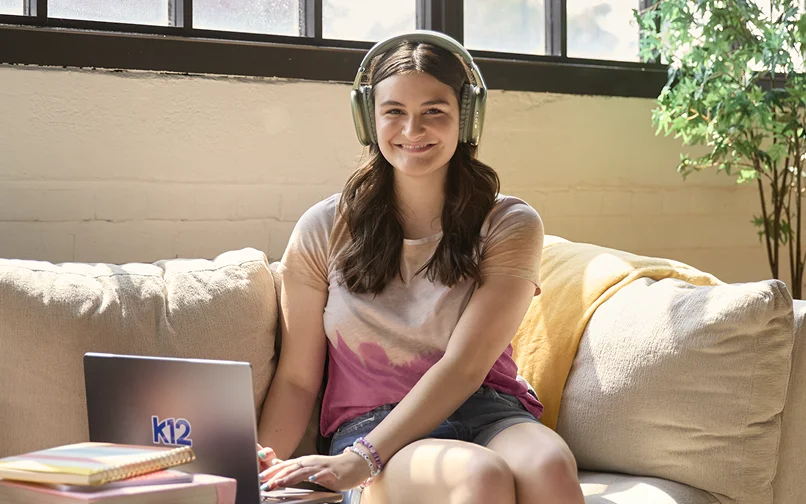 Student wearing a light green pair of headphones while working with her laptop