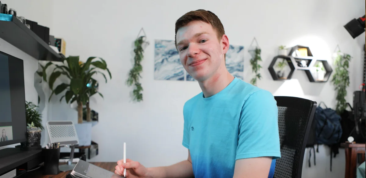 Student taking notes at home wearing a light blue shirt