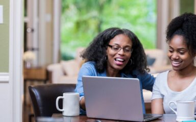 Student learning at a desk in a bright home study space with a laptop.